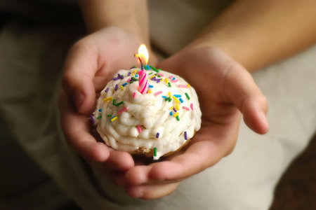 A young childs hands holding a special birthday cupcake.