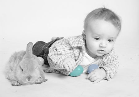 Little baby boy with Easter bunny and colorful eggsの写真素材