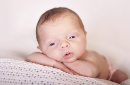 Newborn baby in a cute position with blue eyes wide open