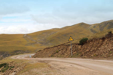View of mountains with the dirt road in Tibet, Chinaの写真素材