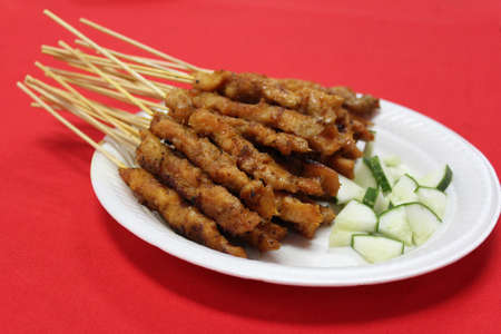 Satay or sate skewered and grilled meat served with cucumberの写真素材