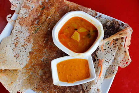 Rava dosa or Ravvattu or Rave Dose is an Indian crepe of South India serve with curry and chilli sauceの写真素材