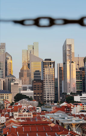 Chain link as blur foreground across Singapore skyline from Chinatown in sunsetのeditorial素材