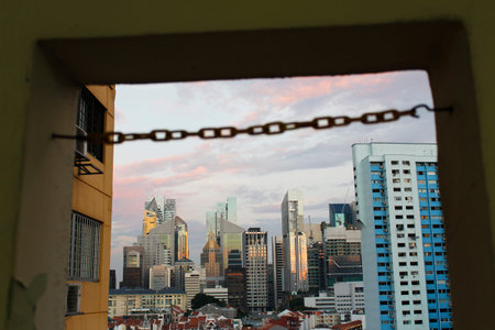 Chain link as blur foreground across Singapore skyline from Chinatown in sunset