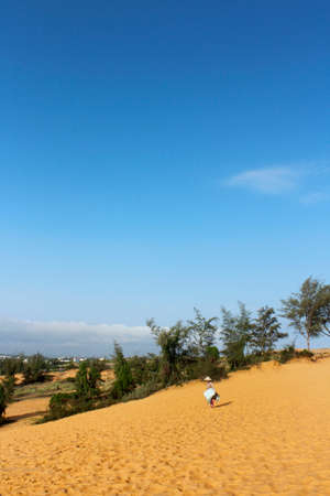 Vietnamese woman with her slide board for rent at Red Sand Dunes, Mui Neの写真素材