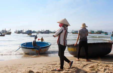 Mui Ne, Vietnam - June 27, 2017: Crowded scene of daily early morning fish market on beach with the Vietnamese woman walk byのeditorial素材