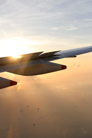 Dramatic cloudscape with the airplane's wing during sunrise from the airplane's window