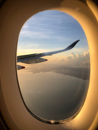 Dramatic cloudscape with the airplane's wing during sunrise from the airplane's window