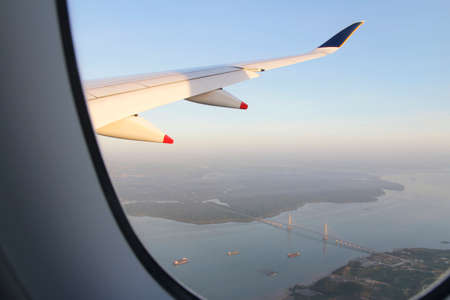 Singapore landscape with the airplane's wing during sunrise from the airplane's windowの写真素材