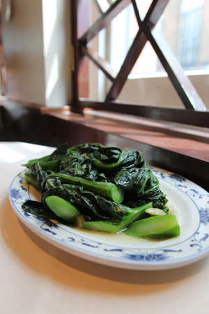 Stir fried Chinese broccoli (Gai lan) with garlic on a plate in a Chinese Restaurantの写真素材