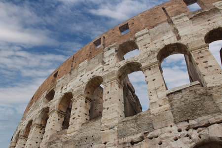 The exterior facade of the Colosseum or Coliseum with the arches against blue clear sky in Rome,...