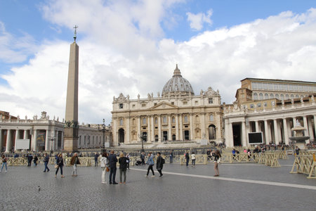 Tourists walking around the Peter's Square and St. Peter's Basilica with the dramatic cloud in a...