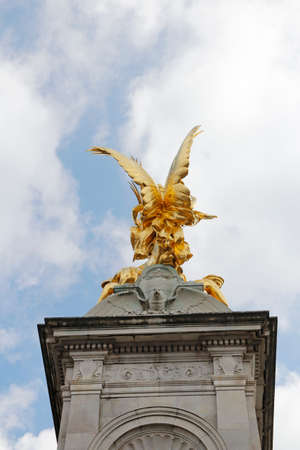 Gilded Winged Victory at the top of the Victoria Memorial in front of Buckingham Palace in a sunny dayの写真素材