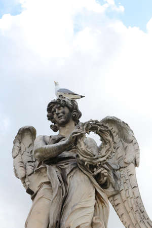 Angel Carrying the Crown of Thorns by Gian Lorenzo Bernini and a seagull stand on the top statue at Castel Sant'Angelo, Rome, Italyのeditorial素材