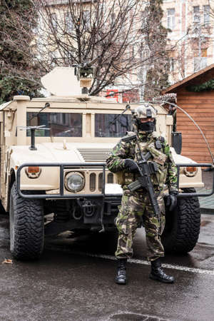 Fully equipped Romanian special operations soldier in front of an armored transport vehicle.のeditorial素材