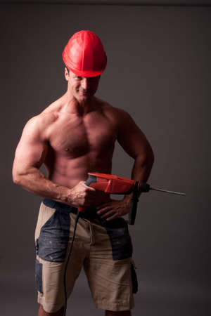 muscular construction worker with drillの写真素材