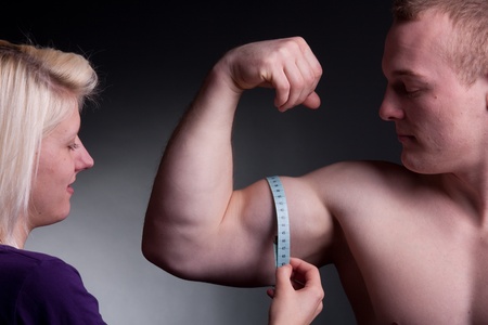 bodybuilder with a measuring tape around his bicepの写真素材