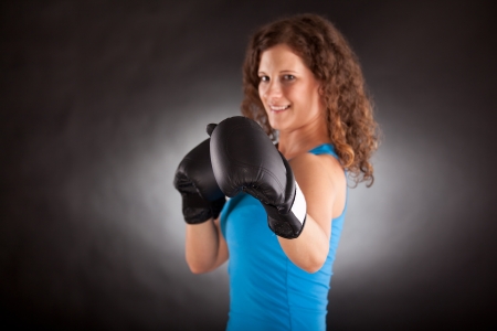Young beautiful sporty woman with box gloves -focus on gloveの写真素材
