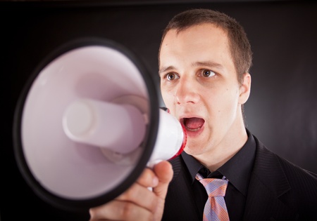 businessman shouting through megaphone in studioの写真素材