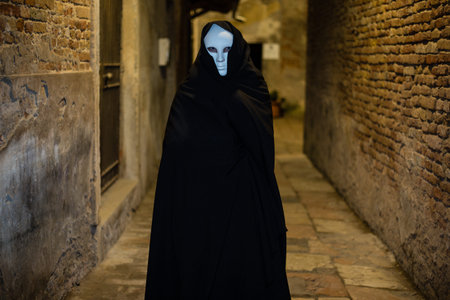 Woman in dark halloween like costume on streets of Venice during carnival