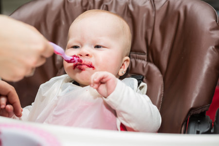 baby girl eating beetroot at homeの写真素材