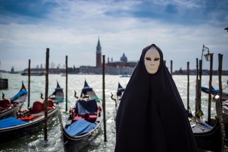 man in dark halloween like costume on streets of Venice during carnivalの写真素材