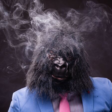 businessman wearing gorilla mask and smoking cigarの写真素材