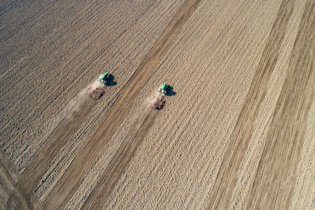 Aerial view of tractor plowing farm field in preparation for spring plantingの写真素材