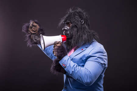 businessman wearing gorilla mask and screaming to megaphoneの写真素材
