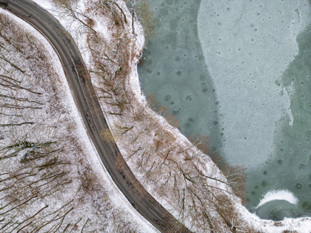Aerial top view of frozen lake and curvy roadの写真素材