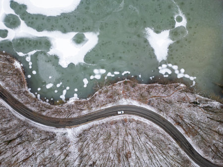 Aerial top view of frozen lake and curvy roadの写真素材