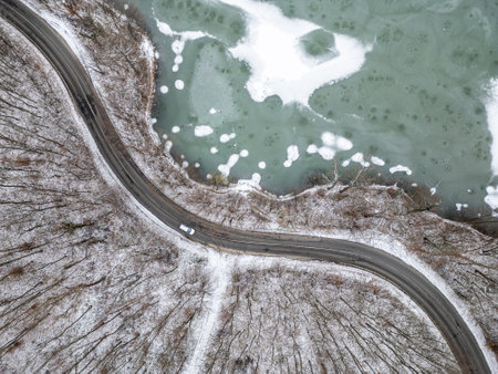 Aerial top view of frozen lake and curvy roadの写真素材