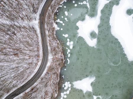 Aerial top view of frozen lake and curvy roadの写真素材