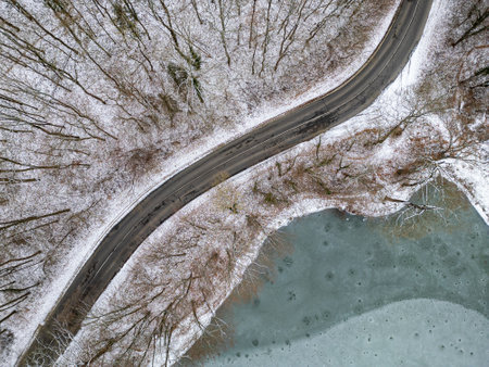 Aerial top view of frozen lake and curvy roadの写真素材