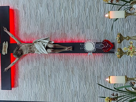 Jesus Christ crucified on a wooden cross in a church with a red light.の写真素材