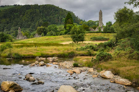 Ireland landscape with a river in the foreground and a cemetery and defensive tower in the background.の写真素材