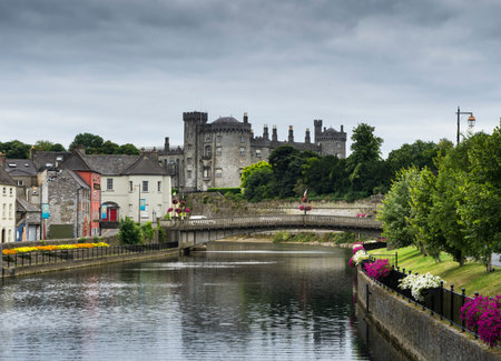 View of part of the city of Kilkenny in Ireland with the castle in the background and cloudy sky.