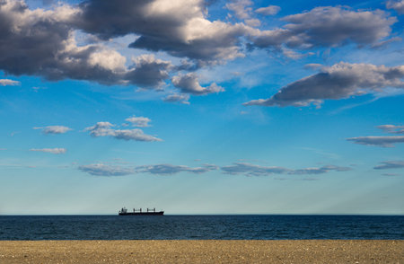 View of blue sky with clouds at sunset over a beach in Almeria with a boat on the horizon line of...