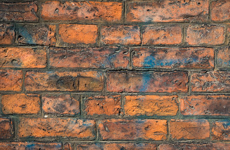 Brick wall in very textured brown tones stained with blue paint.の写真素材