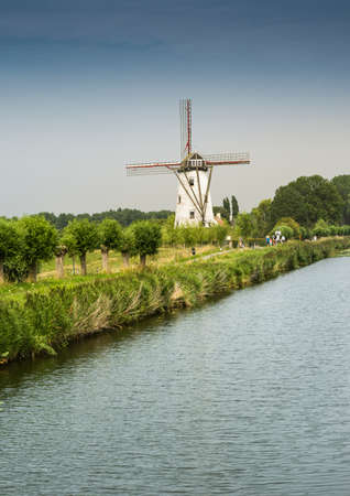 View of a river with an old traditional mill on the shore near the Belgian city of Damme.のeditorial素材