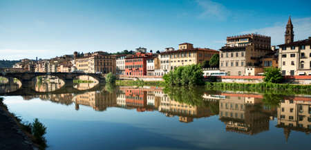 Panoramic view of the city of Florence on the banks of the Arno river with the reflection of the colored houses in the water.の写真素材