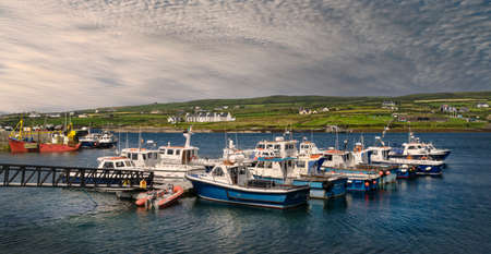 Panoramic view of the harbor in the Irish village of Portmagee in County Kerry, with several fishing boats in the foreground.のeditorial素材
