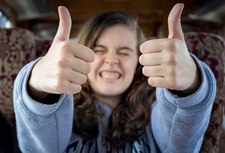 Long-haired teenage girl with her face out of focus in the background of the image and her hands...