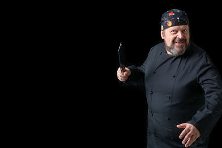 Portrait of cook with knife in hand with black background and copy space on the left side. Expressions of concept.の写真素材
