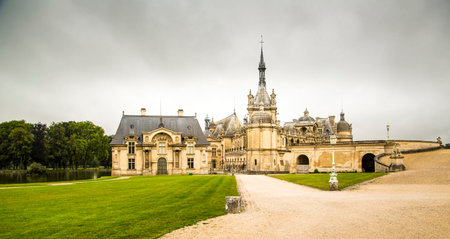 Chantilly, France, 08,26,2021: Panoramic view of the ChÃ¢teau de Chantilly reflected in the water of the river with light clouds in the sky.のeditorial素材