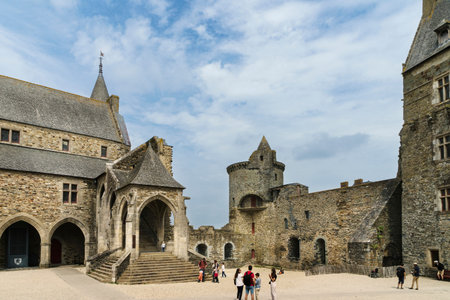 Partial view of the castle of the French town of Vitre on a sunny day and light clouds with tourists in the central courtyard of the castle.のeditorial素材