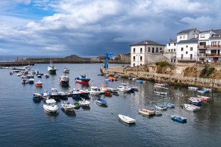 View of the fishing port of the Asturian town of Tapia de Casariego at sunset under cloudy skies.のeditorial素材