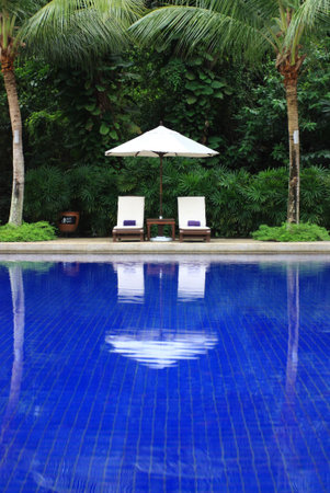 White trestle-beds with umbrella near the swimming poolの写真素材