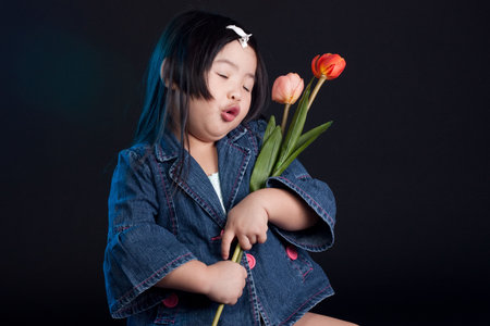 Cute little chinese girl holding a flowerの写真素材