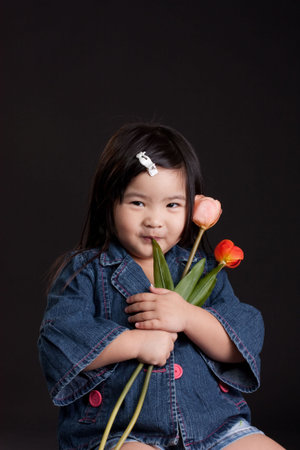 Cute little chinese girl holding a flowerの写真素材